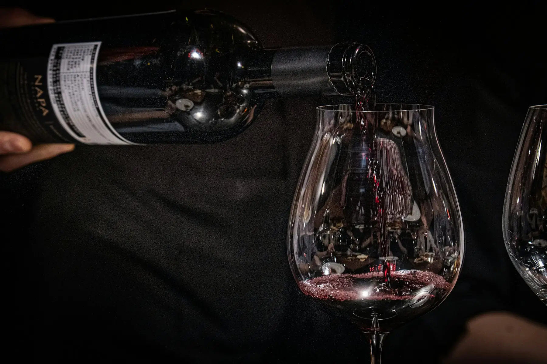 Red wine being poured into a large glass against a dark background