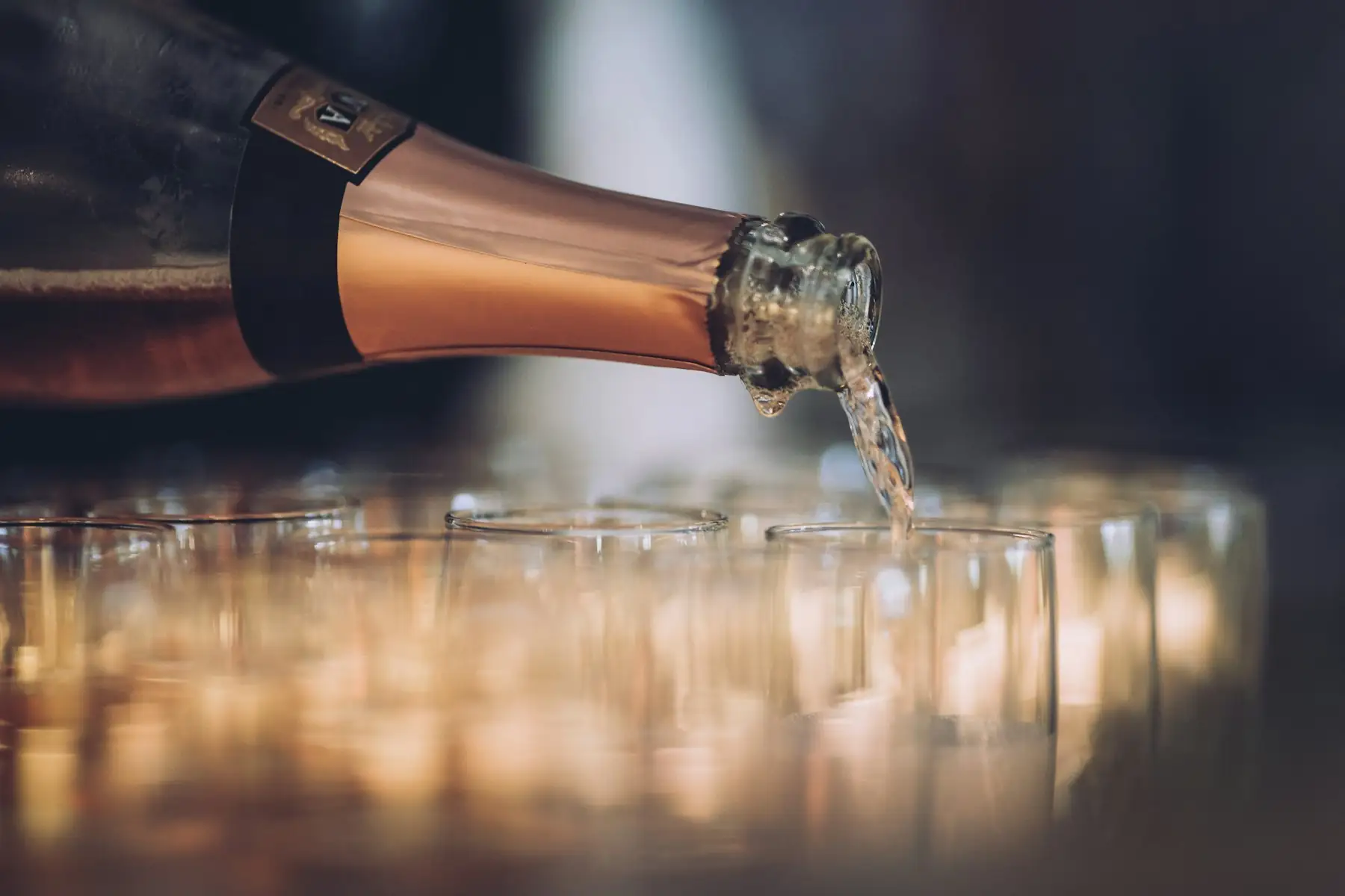Champagne being poured into a row of glasses