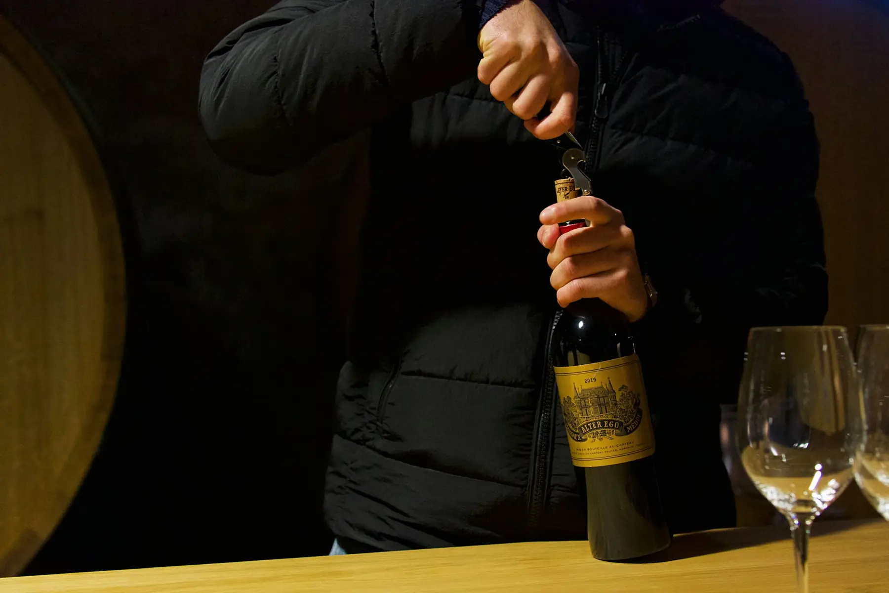 A man opening a bottle of red wine with a waiter's corkscrew